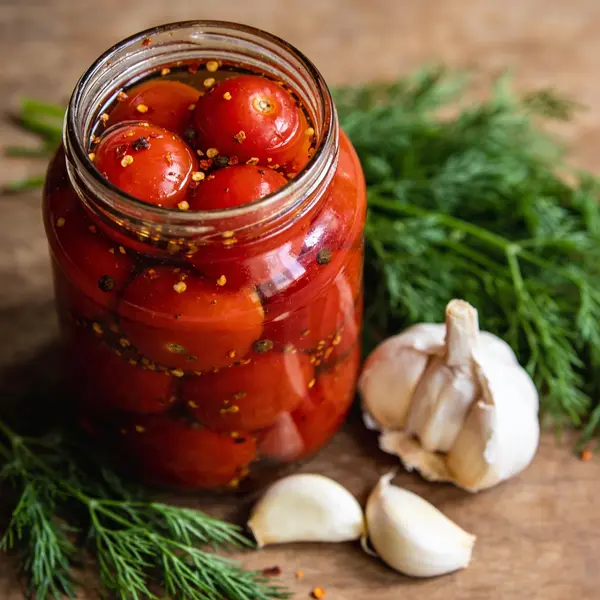 Банка с маринованными красными помидорами и специями.